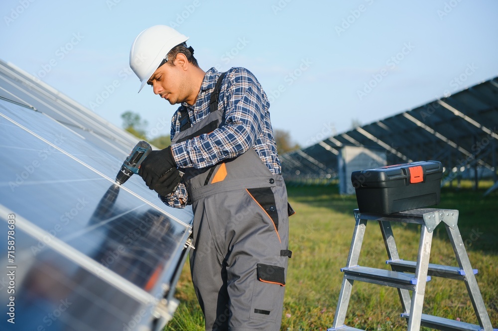 An Indian worker in uniform and with tools works on a solar panel farm An Indian worker in uniform and with tools works on a solar panel farm