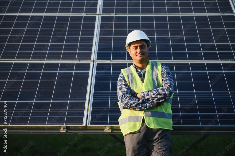 Indian man in uniform on solar farm. Competent energy engineer controlling work of photovoltaic cells Indian man in uniform on solar farm. Competent energy engineer controlling work of photovoltaic cells