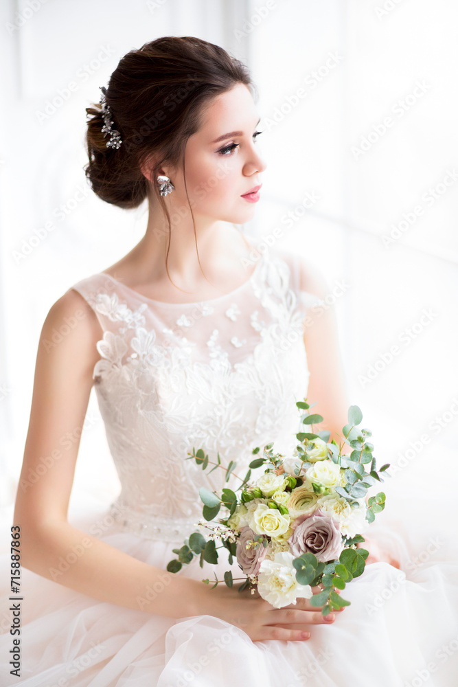 Naklejka premium Beautiful brunette woman with bouquet posing in a wedding dress
