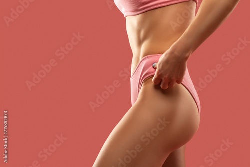 A slender swarthy woman in pink underwear on a pink background. Healthy lifestyle, sport and diet. photo