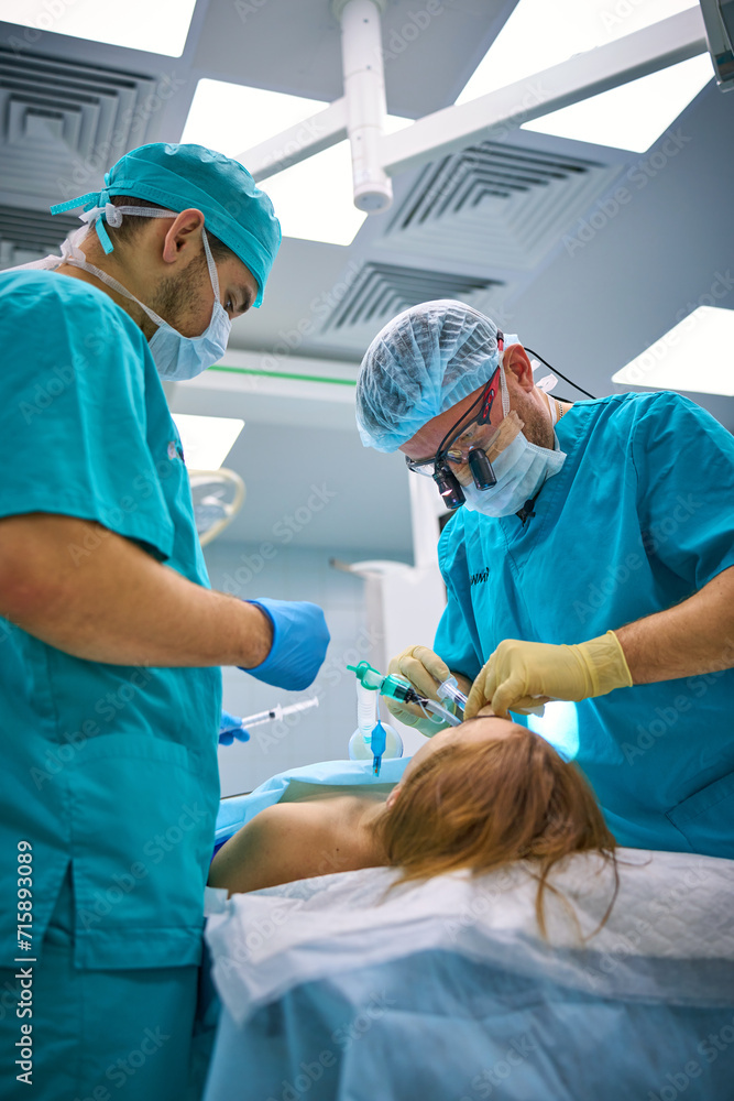 Plastic surgeons perform surgery on a patient Plastic surgeons perform surgery on a patient