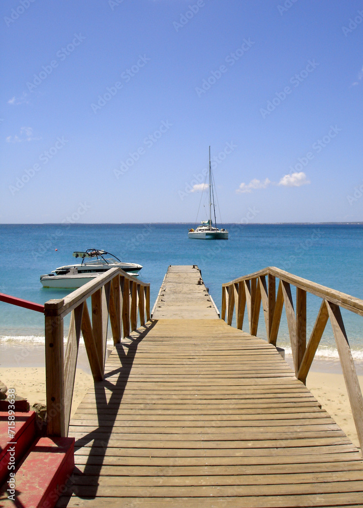 St Marteens caribbean pier over beach with yacht in background