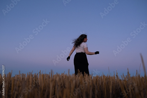 Mujer posando en descampado con viento durante el atardecer