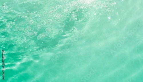 closeup of mint green clear calm water surface texture with splashes and bubbles trendy abstract summer nature background mint colored waves in sunlight