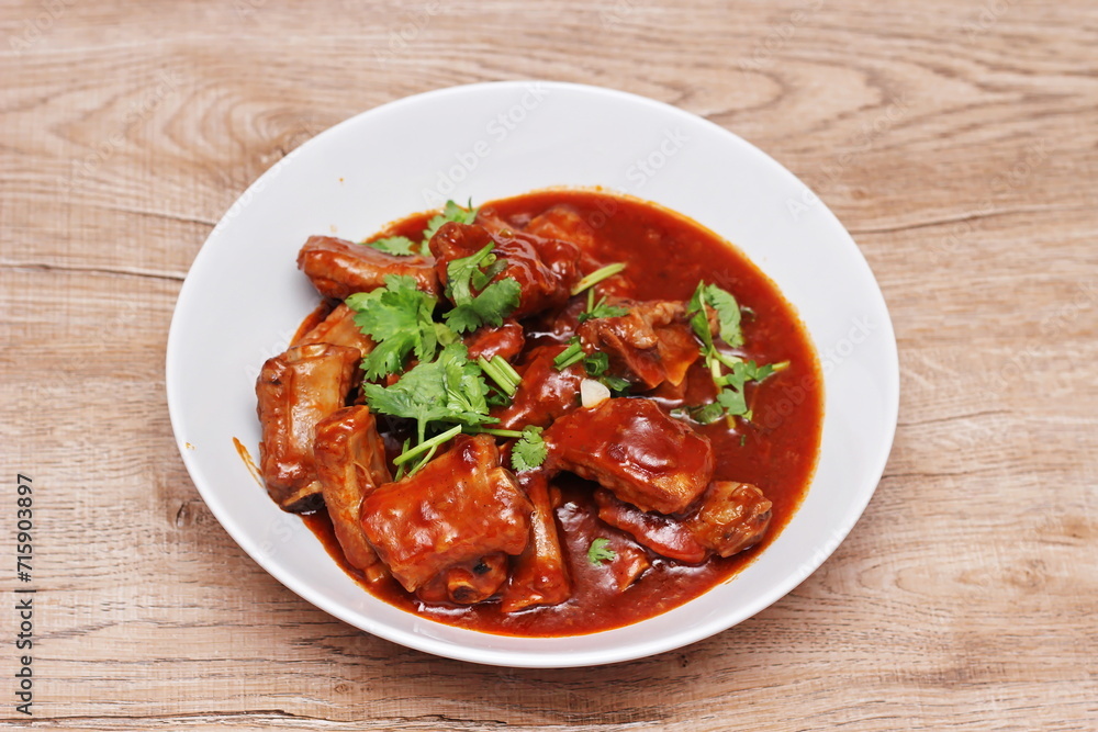 Chinese Red Soup Pork Ribs served on a white plate, a popular Chinese dish, made from sliced pork ribs and tomato sauce. Chinese Red Soup Pork Ribs served on a white plate, a popular Chinese dish, made from sliced pork ribs and tomato sauce.