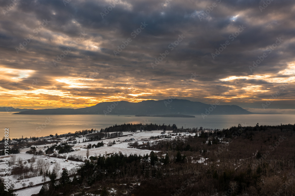 Winter sunset over Orcas Island, Washington in the Pacific Northwest. Dramatic clouds and a snowy landscape highlight the winter season in the San Juan Islands located in the Salish Sea.