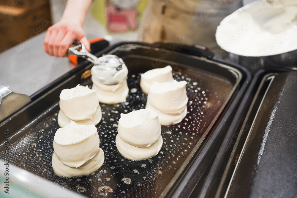 Freshly whipped meringues being prepared on a hot griddle.