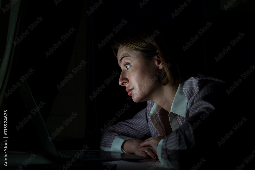 Side view of young tired businesswoman working on laptop at night. Work from home concept Side view of young tired businesswoman working on laptop at night. Work from home concept