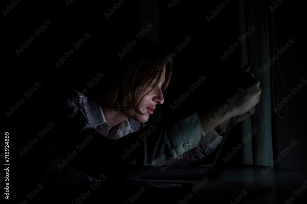 Side view of young tired businesswoman working on laptop at night. Work from home concept Side view of young tired businesswoman working on laptop at night. Work from home concept