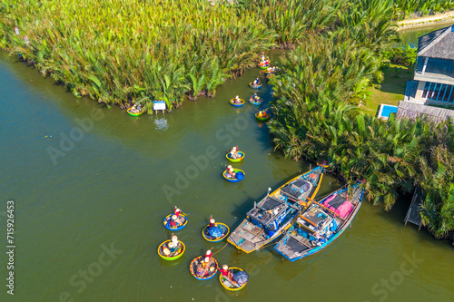 Aerial view of a coconut village basket boat tour. Palms forest in Hoi An, Cam Thanh, Vietnam. Tourists having an excursion and fun in Thu Bon river photo