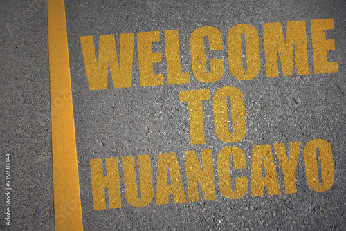 asphalt road with text welcome to Huancayo near yellow line. photo