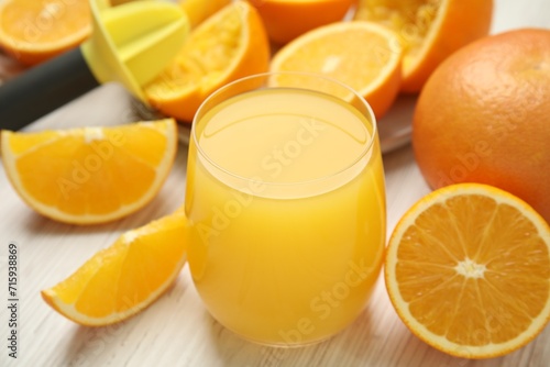 Freshly made juice, oranges and reamer on wooden table, closeup