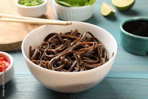Tasty buckwheat noodles (soba) served on light blue wooden table, closeup
