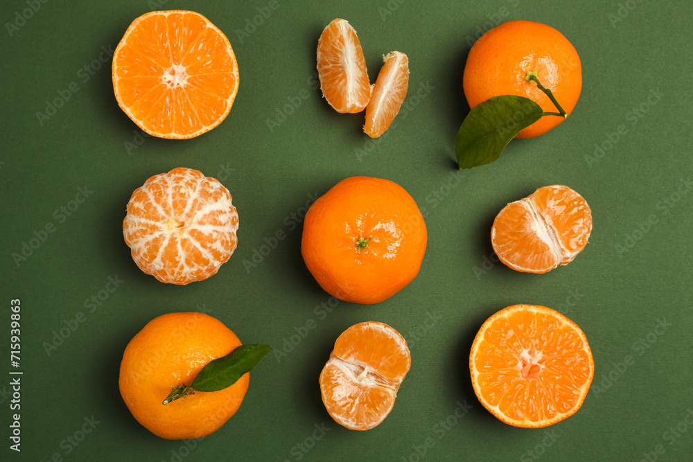 Delicious tangerines with leaves on green background, flat lay Delicious tangerines with leaves on green background, flat lay