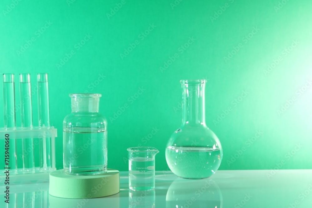 Laboratory analysis. Different glassware on table against green background, space for text Laboratory analysis. Different glassware on table against green background, space for text