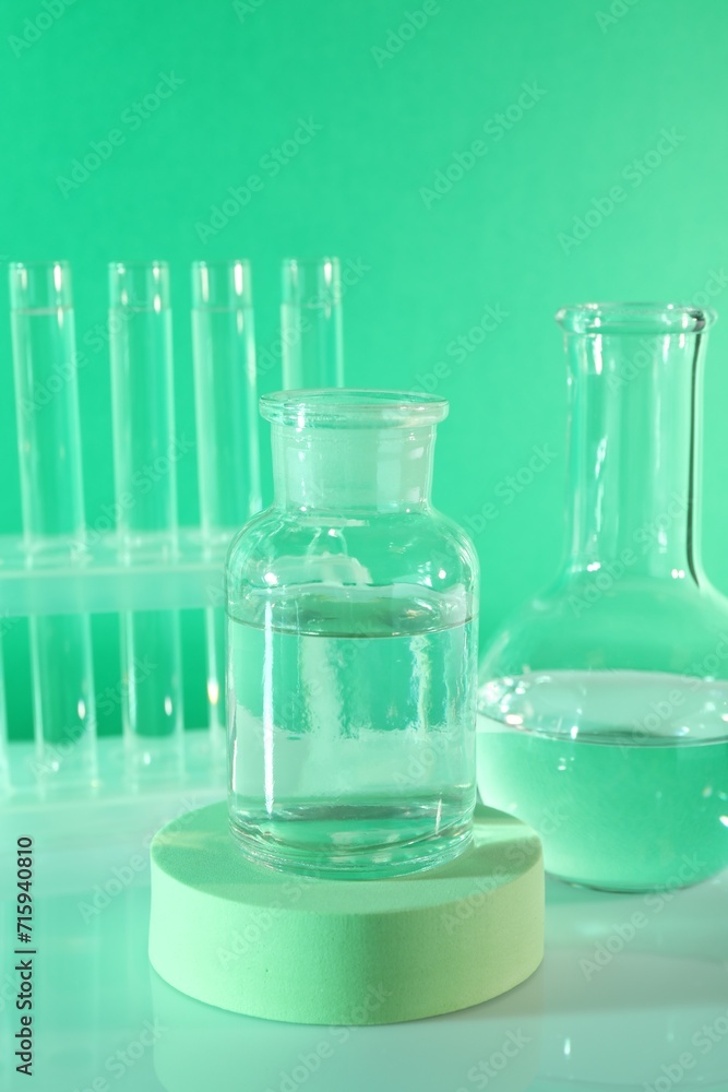 Laboratory analysis. Glass flasks and test tubes on table against green background Laboratory analysis. Glass flasks and test tubes on table against green background