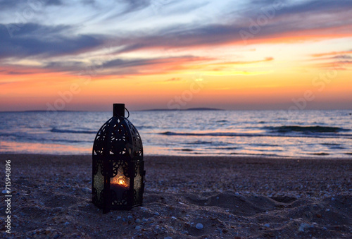 A burning lantern on the seashore against the sunset background, a candle, a lighthouse, a beautiful seascape, evening.