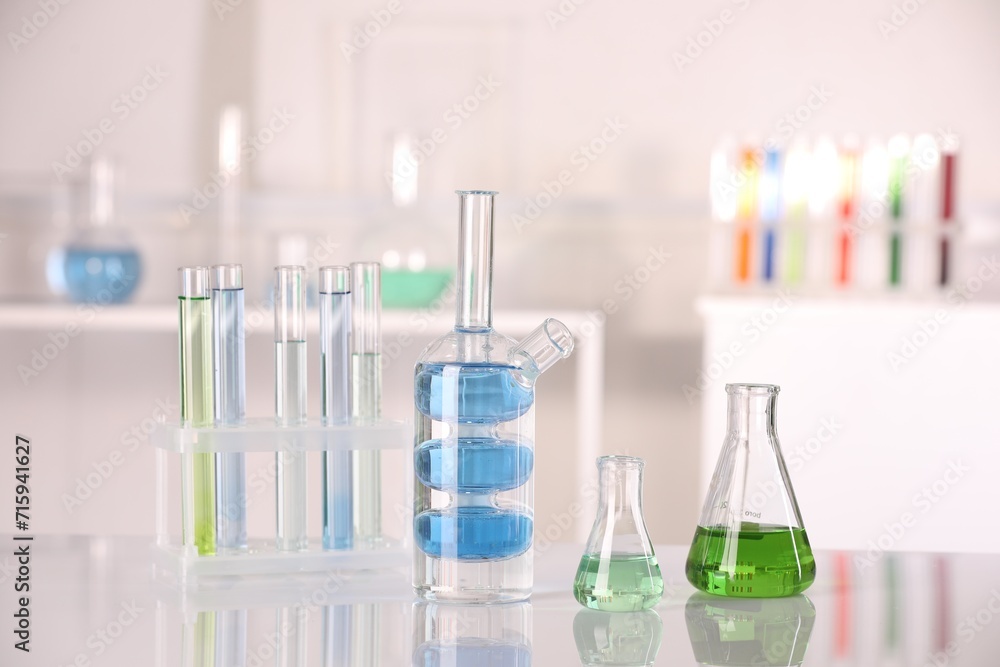 Laboratory analysis. Different glassware with liquids on white table indoors Laboratory analysis. Different glassware with liquids on white table indoors