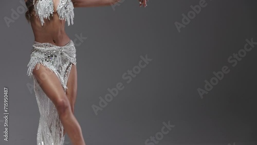 Belly and body part of a graceful woman dancing oriental dance in the studio, making beautiful body movements dressed in white suit. Ballet Female Dancer Performing a Choreography. 4k footage photo