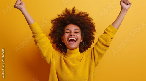 Exuberant woman in yellow, arms raised in victory