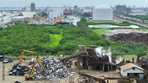 Old vehicle utilization junkyard with claw crane manipulator machines lifting and disposing cars for scrap metal. Transport equipment at crashed auto disposal site