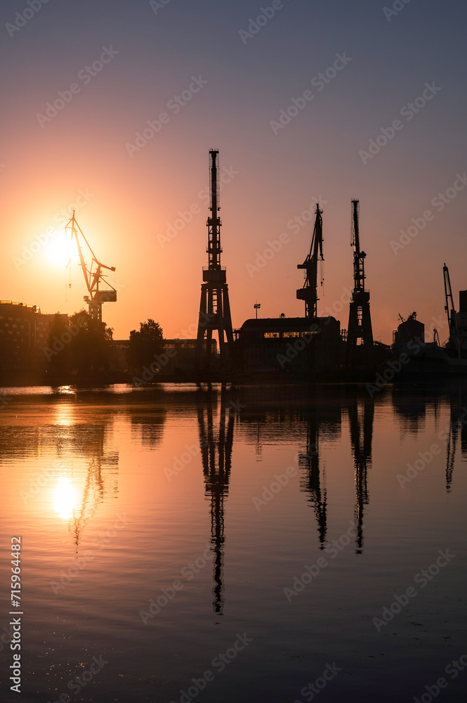 Silhouettes of cranes in the shipyard during sunrise