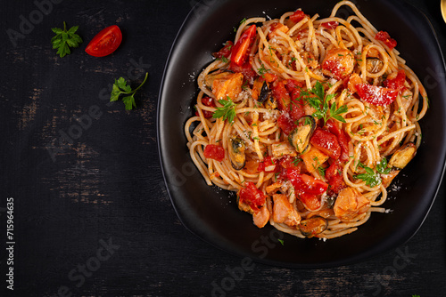 Classic italian pasta spaghetti marinara with mussels and salmon on dark table. Spaghetti pasta with sauce marinara. Top view, overhead