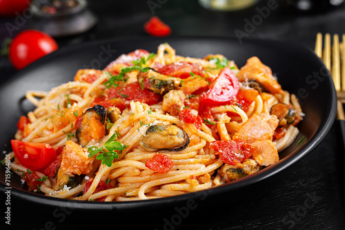 Classic italian pasta spaghetti marinara with mussels and salmon on dark table. Spaghetti pasta with sauce marinara.