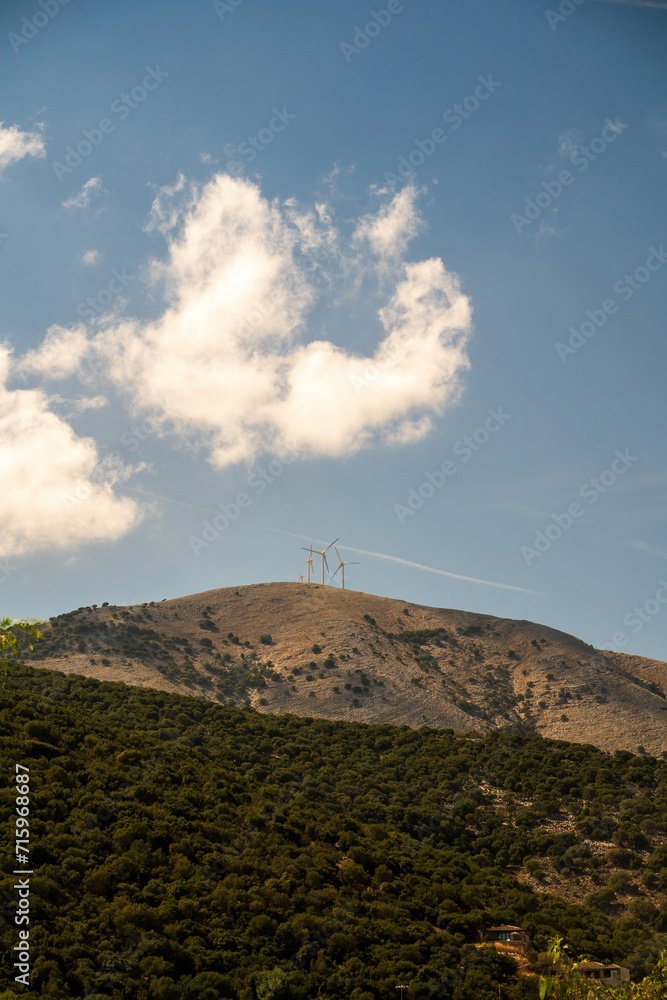 wind plant turbine green energy on Greece mountains against blue cloudy sky