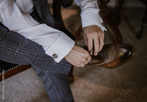 Man lacing up his shoes getting ready on his wedding morning in a checked suit