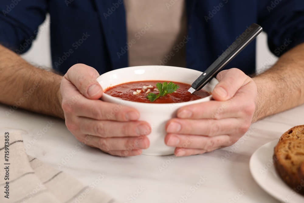 Man with delicious tomato soup at light table, closeup Man with delicious tomato soup at light table, closeup