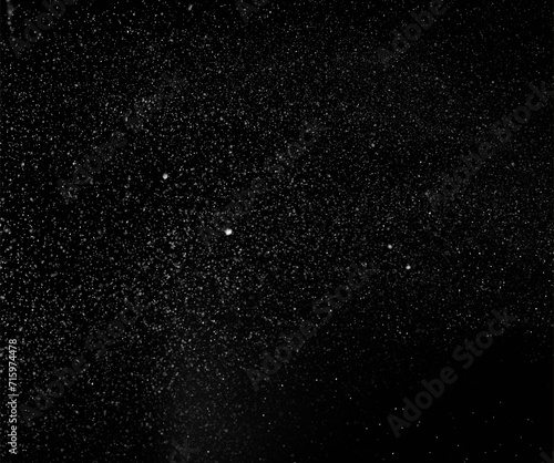 Freezing falling snowflakes or stardust in air on black background for overlay blending mode. Stopping the movement of white powder on a dark background, selective focus