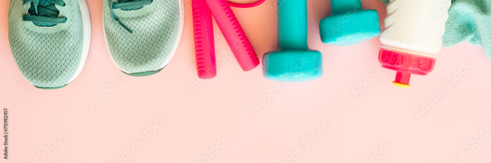 Fitness equipment on pink background, flat lay image. Sneakers, dumbbells, towel and bottle of water. Long banner format. Fitness equipment on pink background, flat lay image. Sneakers, dumbbells, towel and bottle of water. Long banner format.