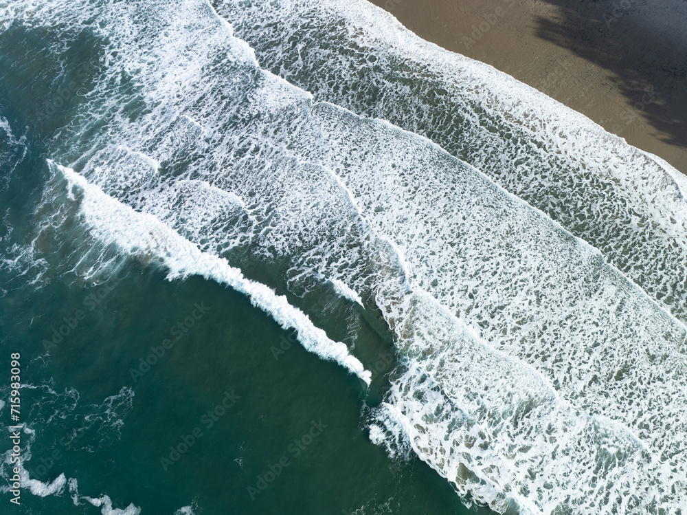 Seen from above, gentle waves create patterns in the water along the coast of Oregon. This scenic region, where forest meets the ocean, is known for its beautiful beaches, sea stacks, and tide pools.