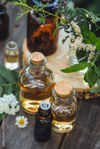 Concept of pure organic essential oil in glass bottles in cosmetology. Moisturising skin care, aromatherapy. Gentle body treatment. Atmosphere of harmony, relax. Wooden background, natural ingredients