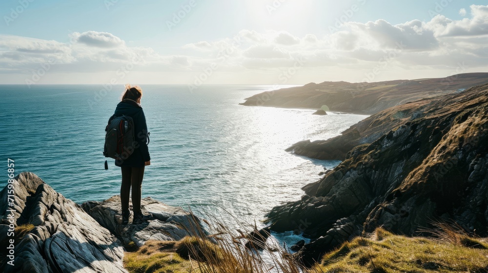 Person stood on a cliff overlooking the sea