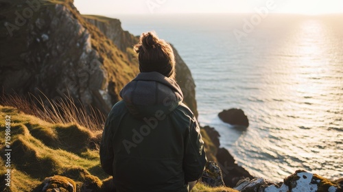 Person stood on a cliff overlooking the sea