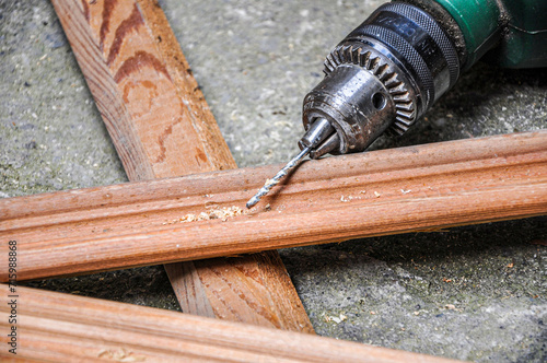 Man holding green drill and drilling lining woods, electric drill-driver photo