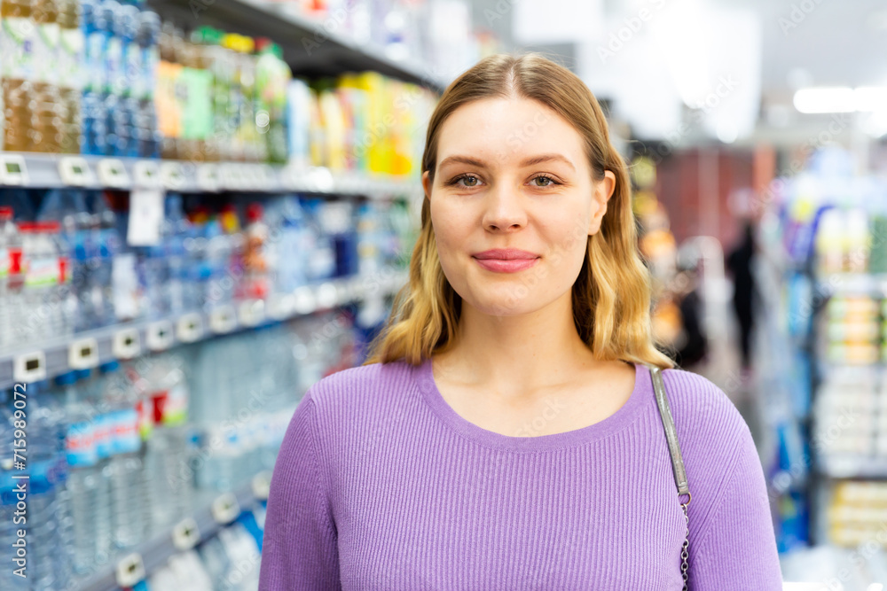 Woman is standing glad after shopping in modern supermarket