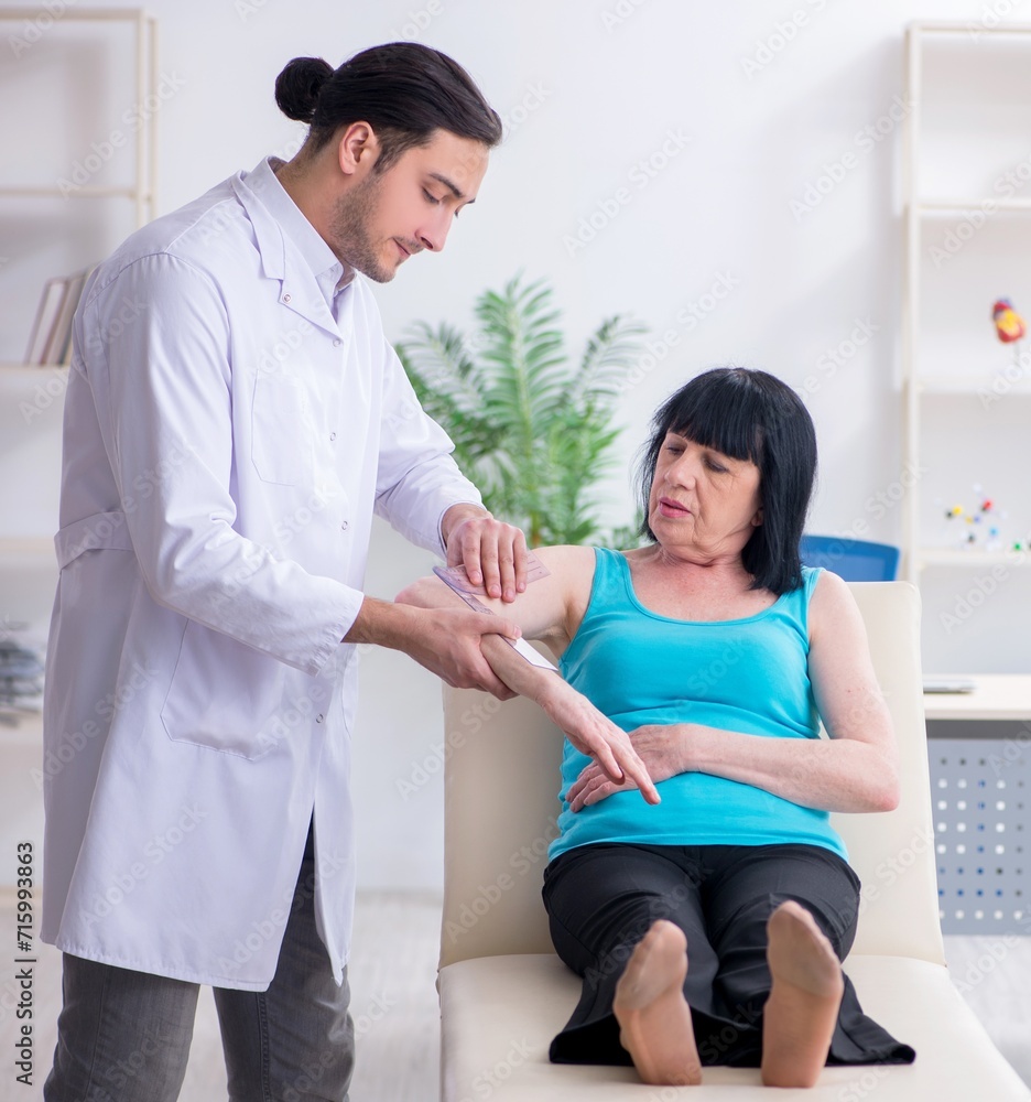Young male doctor examining old female patient Young male doctor examining old female patient
