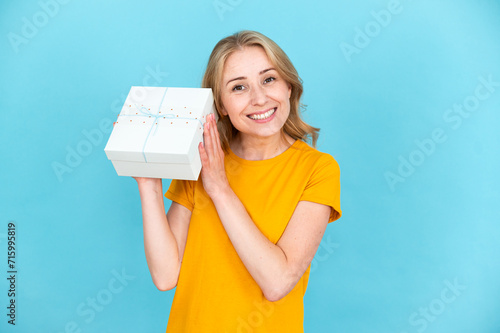 Happy woman with gift box in hands listening noise try to guess what inside photo