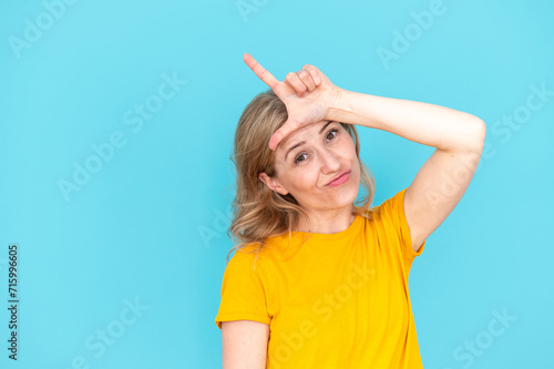 Woman doing loser gesture with fingers on forehead photo