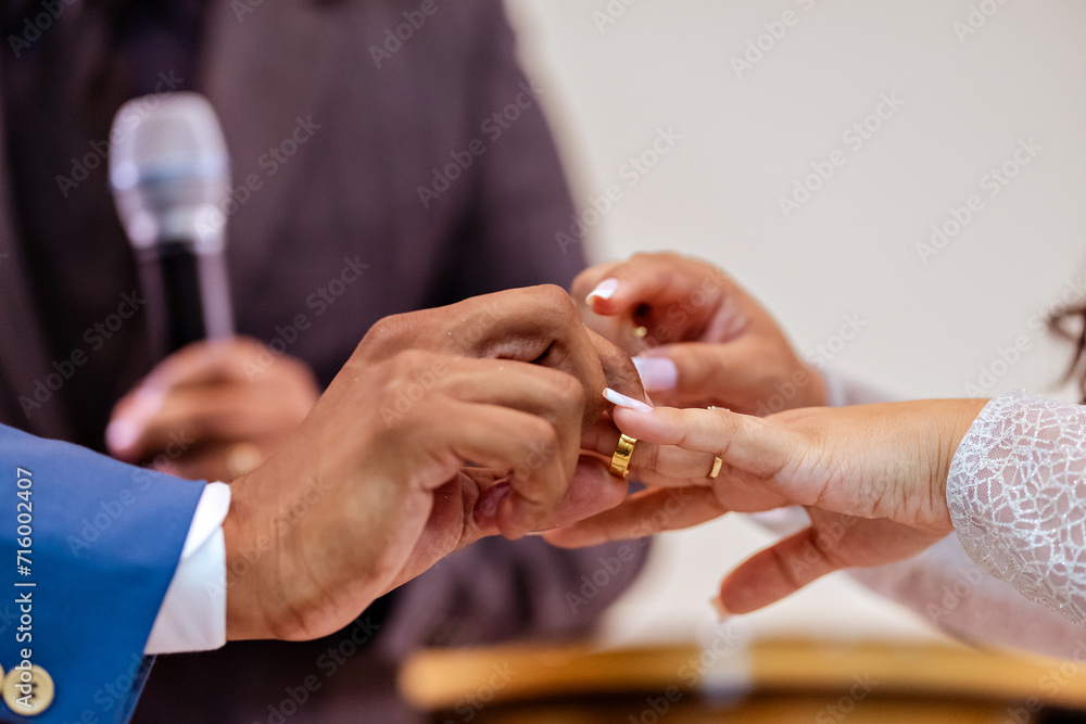 a wedding couple holding hands putting on rings