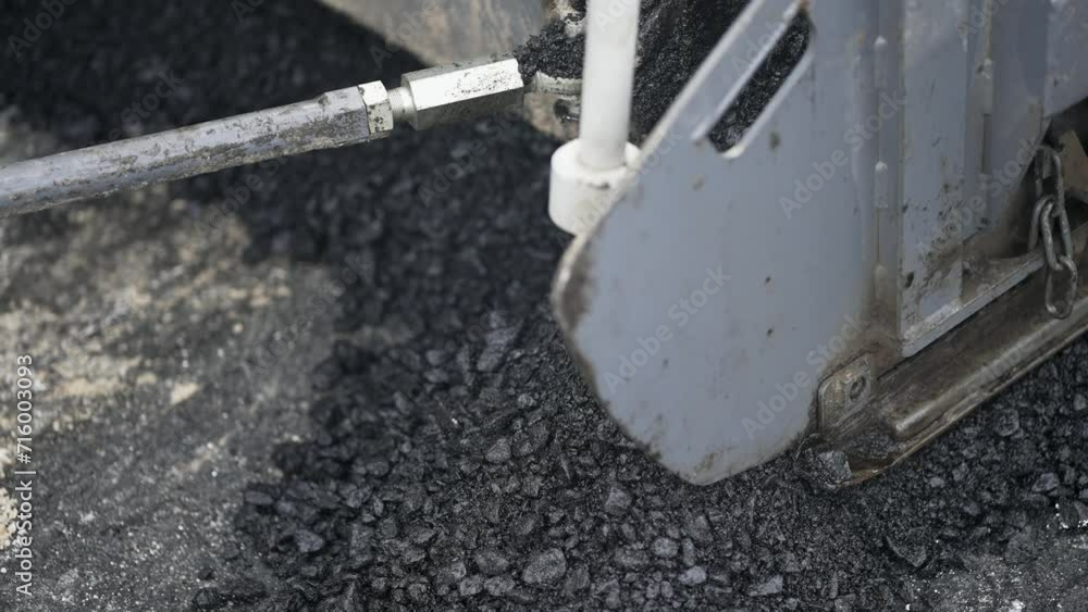 Detail view of machine laying new asphalt coating using hot bitumen. Work of heavy machinery and paver, slow motion Detail view of machine laying new asphalt coating using hot bitumen. Work of heavy machinery and paver, slow motion