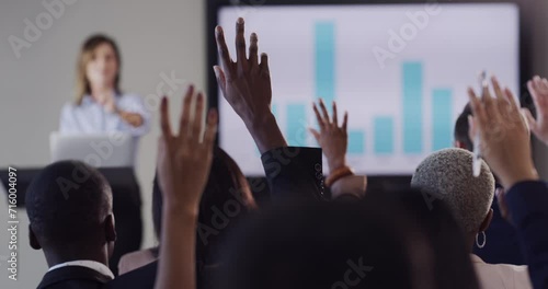 Presentation, meeting and woman with audience question for business seminar, conference and discussion. Raised hands, corporate office and speaker with chart for finance review, report and feedback photo