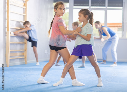 Boy and girl in gym perform basic elements of krav maga self-defense system. Preparation of athletes before competitions