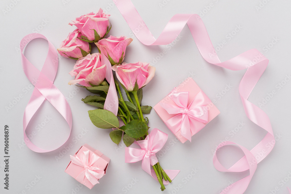 Composition with pink roses, gift box and eight made of ribbon on color background, top view. Women's day concept Composition with pink roses, gift box and eight made of ribbon on color background, top view. Women's day concept