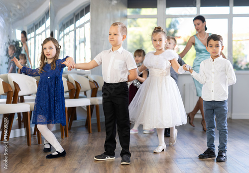 Fotografia Elegantly dressed children, preteen girls and boys performing curtsy and bow dur