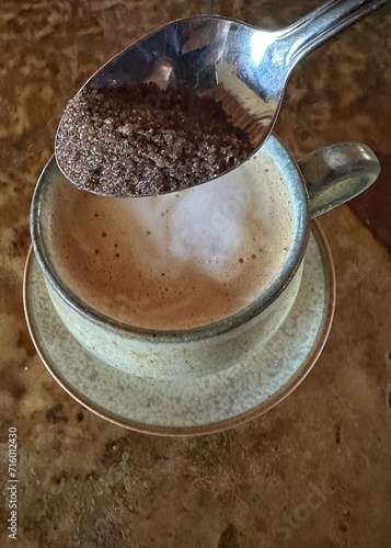 A spoonful of raw sugar about to be added to a cappuccino
