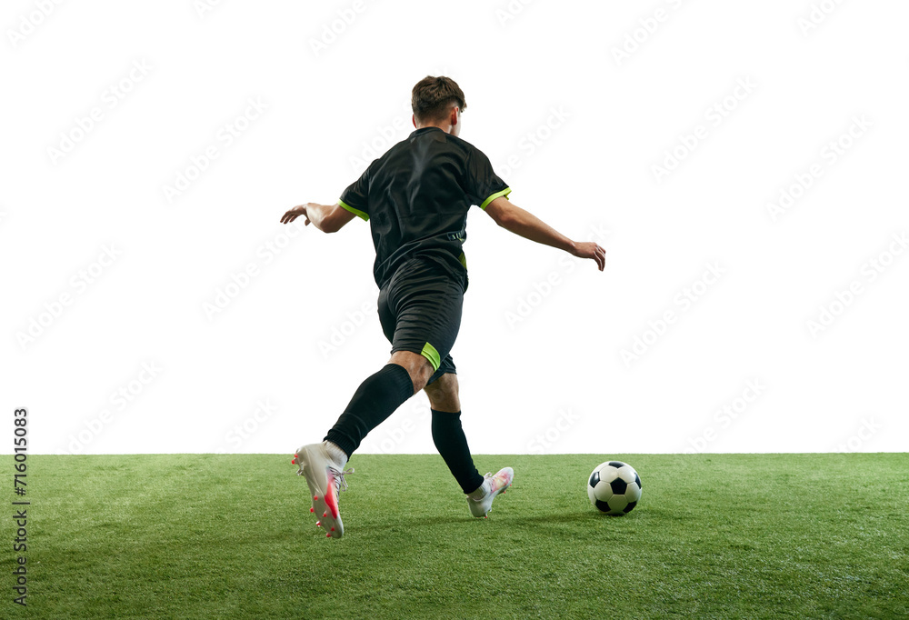 Young man, football player in uniform playing, training, dribbling ball isolated over white background with grass flooring. Concept of sport, game, competition, championship, active lifestyle Young man, football player in uniform playing, training, dribbling ball isolated over white background with grass flooring. Concept of sport, game, competition, championship, active lifestyle